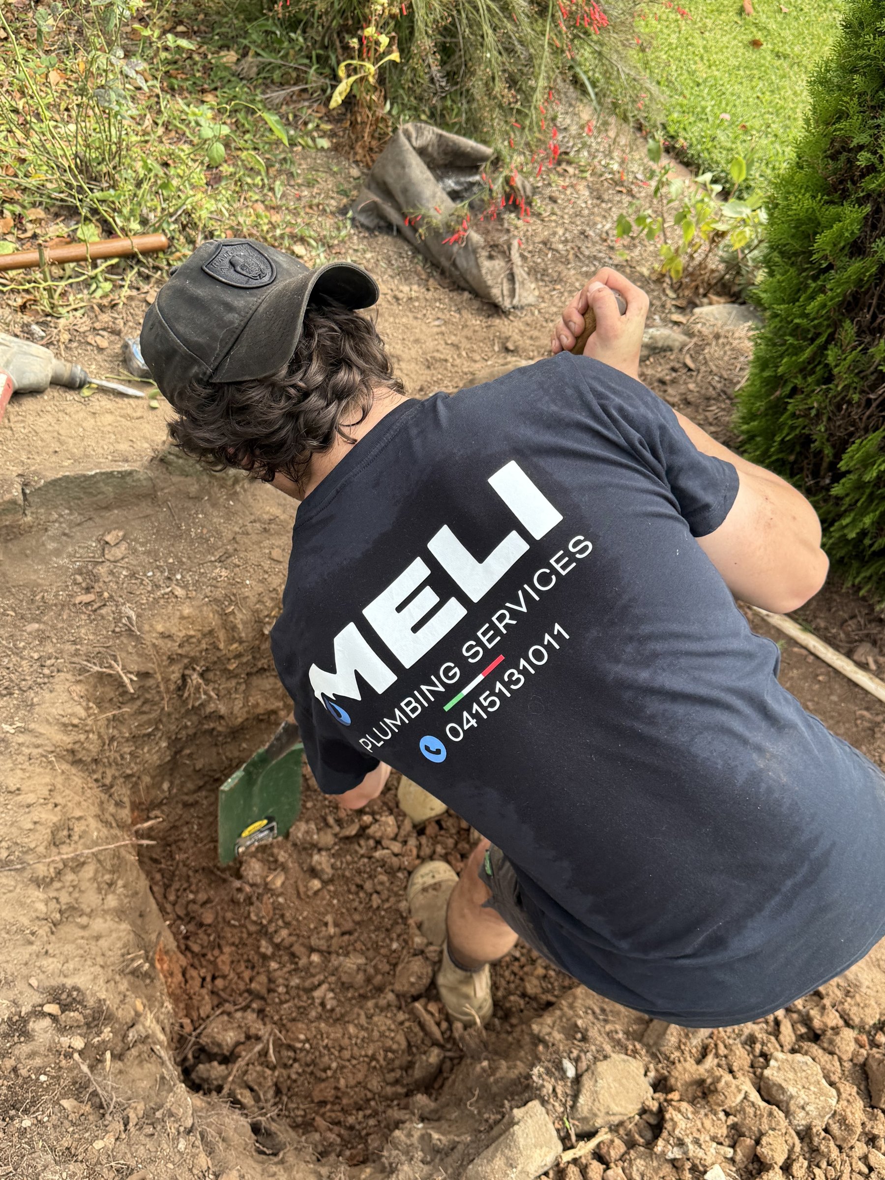 Meli Plumbing Services tradesperson digging a trench on site to access underground pipework